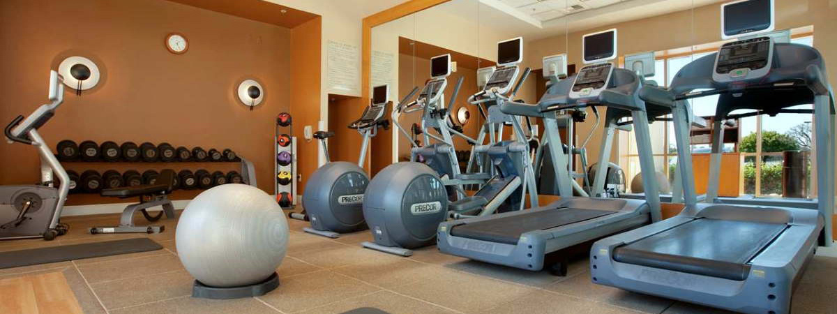Fitness center at Hilton Santa Clara with treadmills, free weights, and cardio equipment